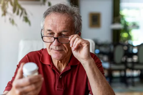 Une personne agée qui lit une boite de médicaments