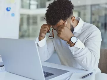 Personne qui à la tête dans ses mains devant son ordinateur